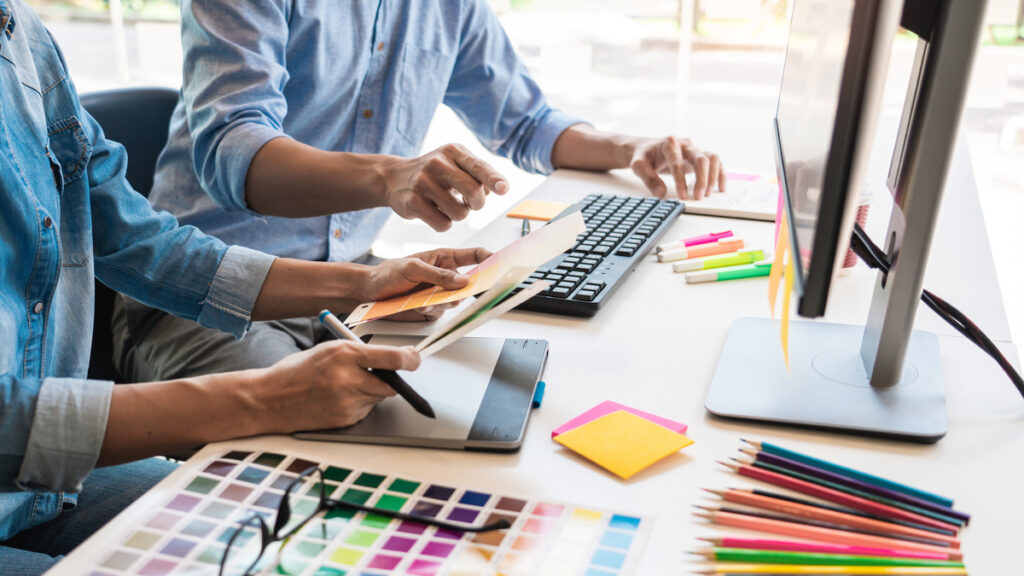 Designers creating cannabis brand identity using compliant color palette and typography.